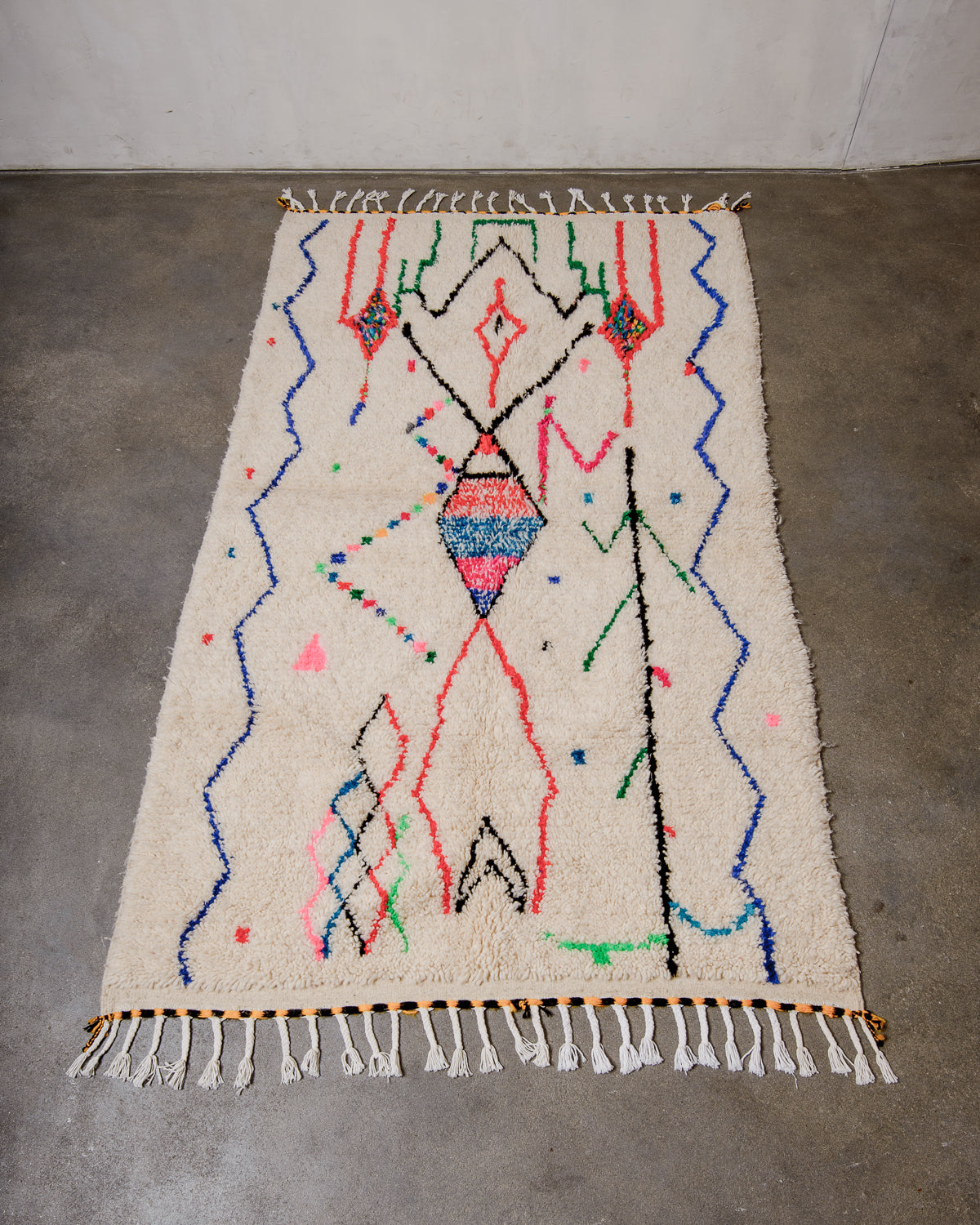 Berberlin Azilal rug made of fluffy wool and cotton, laying flat on a concrete floor.